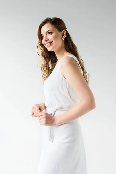 Cheerful girl in dress smiling while standing on white — Stock Photo