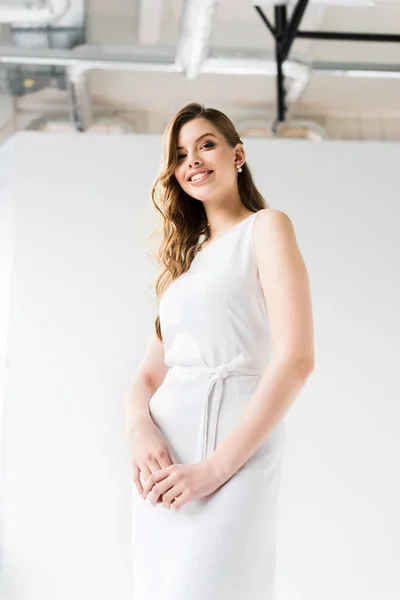Vue à angle bas de jeune femme souriante en robe sur blanc — Photo de stock