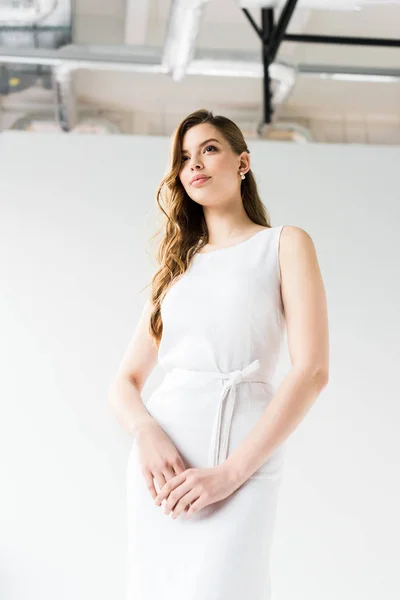 Vue à angle bas de la jeune femme attrayante en robe sur blanc — Photo de stock