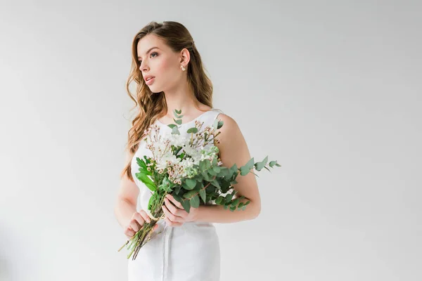 Pensive young woman in dress holding flowers on grey — Stock Photo