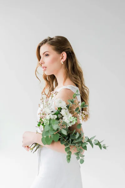 Jeune femme rêveuse en robe tenant des fleurs sur blanc — Photo de stock