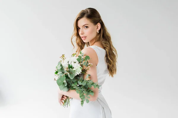 Chica atractiva en blanco sosteniendo flores en blanco - foto de stock