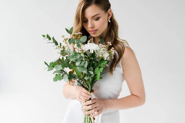 Schöne junge Frau im Kleid, die Blumen auf Weiß betrachtet — Stockfoto