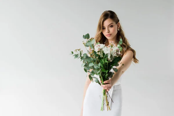 Foco seletivo de menina atraente segurando buquê de flores no branco — Fotografia de Stock