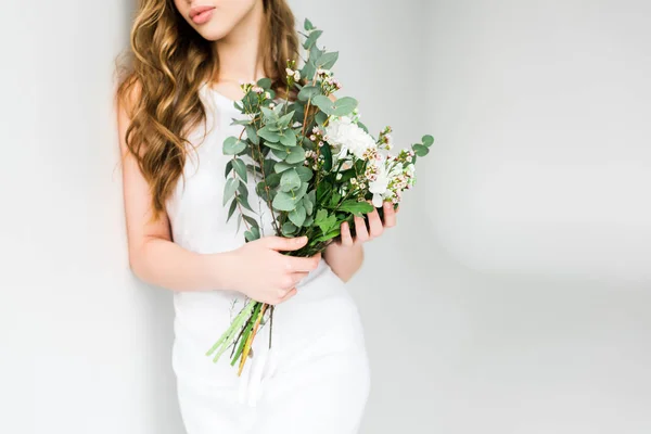 Vista cortada de menina segurando buquê de flores no branco — Fotografia de Stock