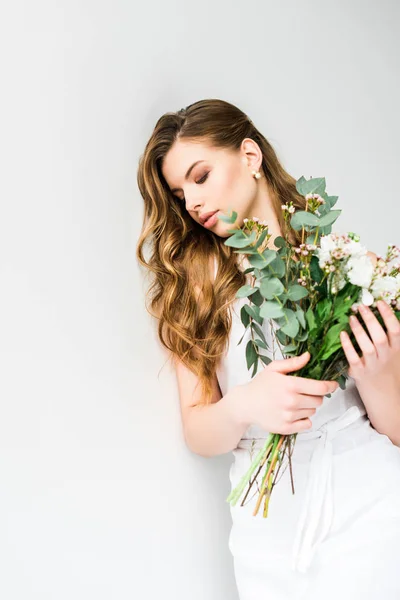 Atractiva joven mujer sosteniendo ramo de flores en blanco - foto de stock