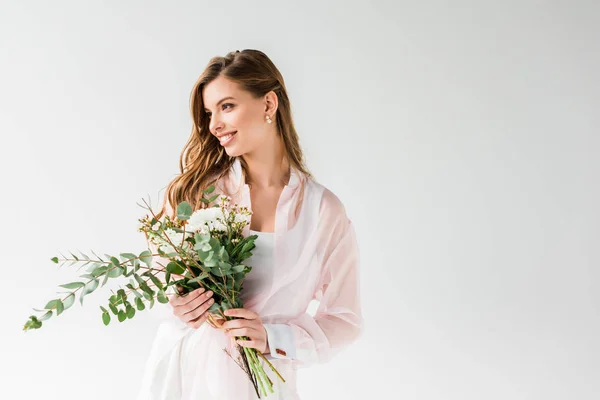 Joyeuse fille tenant des fleurs et des feuilles d'eucalyptus vert sur blanc — Photo de stock
