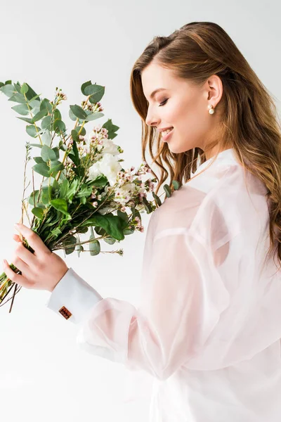 Щаслива жінка пахне квітами з зеленим листям евкаліпта на білому — стокове фото
