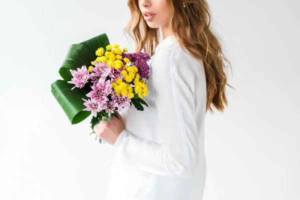 Vista recortada de niña sosteniendo ramo de flores silvestres en blanco - foto de stock