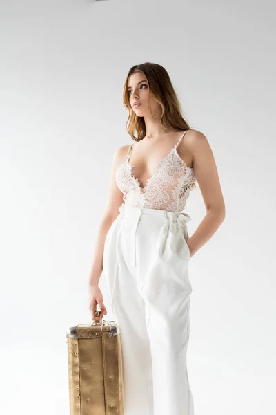Hübsches Mädchen mit Koffer im Stehen mit der Hand in der Tasche auf weiß — Stockfoto