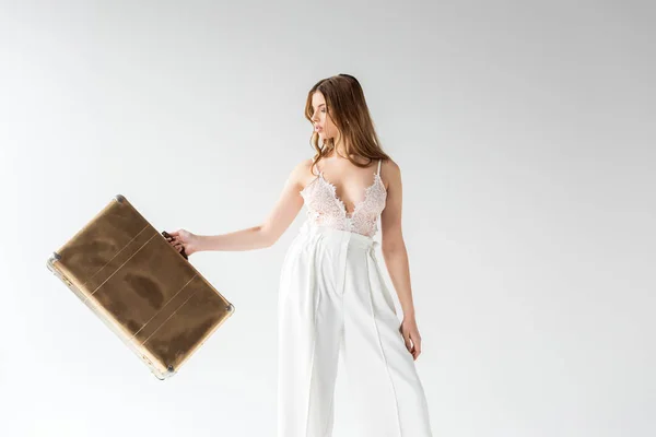 Beautiful girl holding travel bag while standing on white — Stock Photo