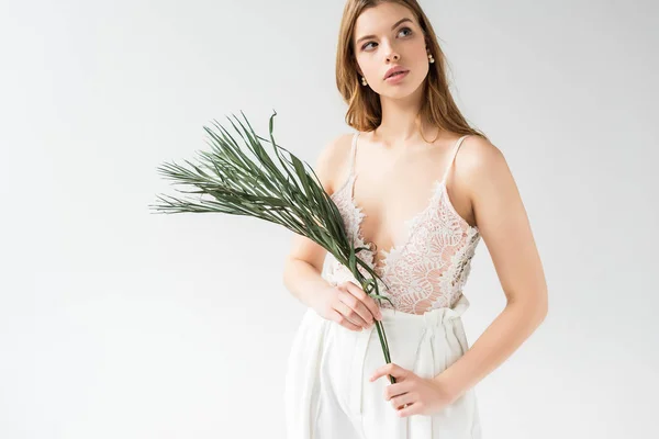 Attraente ragazza sognante che tiene foglia di palma su bianco — Foto stock