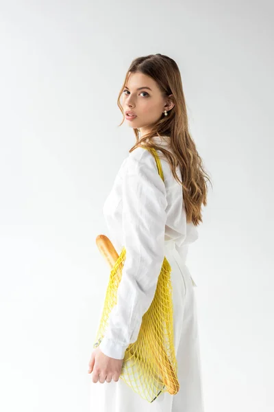 Attractive woman with baguette and bottle of milk in yellow string bag on white — Stock Photo