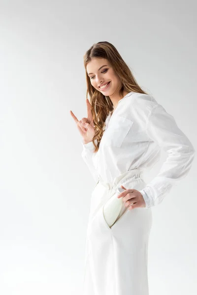 Glücklich attraktive junge Frau steckt Flasche Milch in die Tasche und zeigt Felszeichen auf weiß — Stockfoto