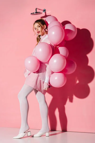 Schöne junge Frau mit Luftballons im Stehen auf rosa — Stockfoto