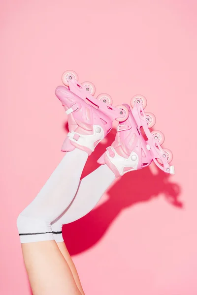 Cropped view of girl wearing long socks and roller-skates on pink — Stock Photo