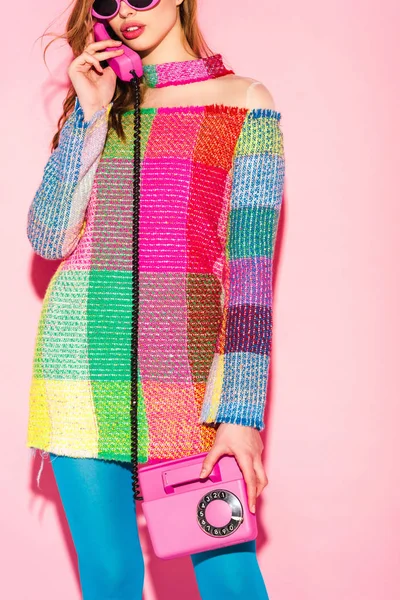 Cropped view of young woman in sunglasses and checkered dress talking on retro phone on pink — Stock Photo