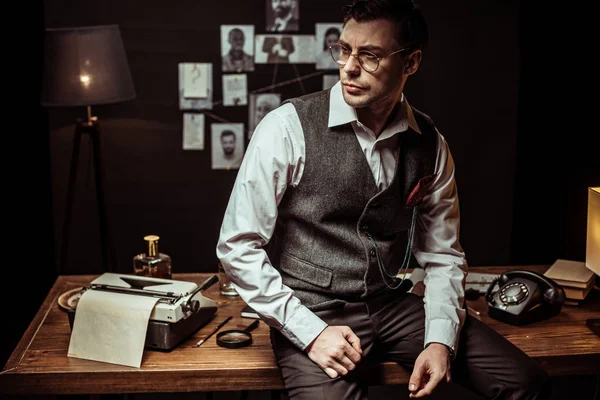 Швидкий детектив в окулярах, сидячи на дерев'яному столі в темному офісі — стокове фото