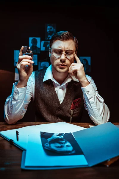 Pensive detective holding lighter with closed eyes in office — Stock Photo