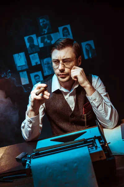 Detective pensativo en gafas sosteniendo cigarros y mirando hacia otro lado en la oficina oscura - foto de stock