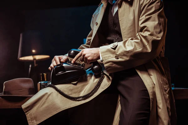 Partial view of man in trench coat holding telephone in office — Stock Photo