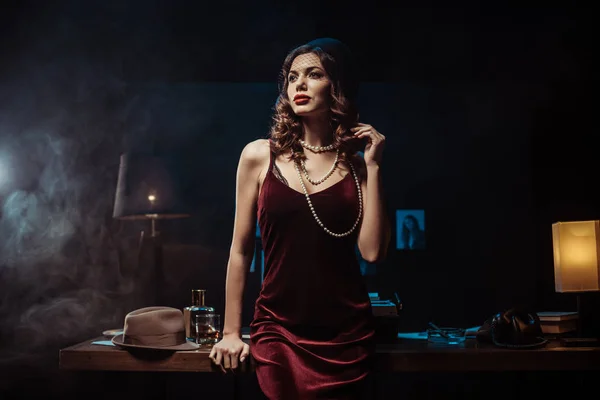 Мрійлива жінка в оксамитовій сукні дивиться в темний офіс — стокове фото
