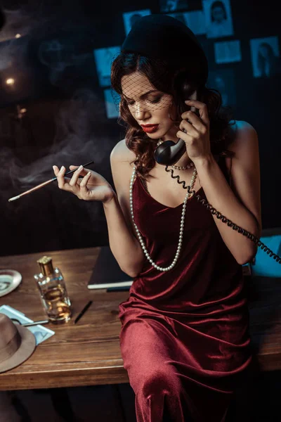 Attractive woman with mouthpiece talking on telephone in dark office — Stock Photo