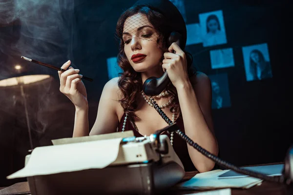 Attractive woman with mouthpiece talking on telephone in dark office — Stock Photo