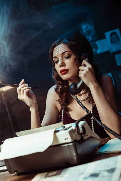 Attractive woman with mouthpiece talking on telephone in dark office — Stock Photo