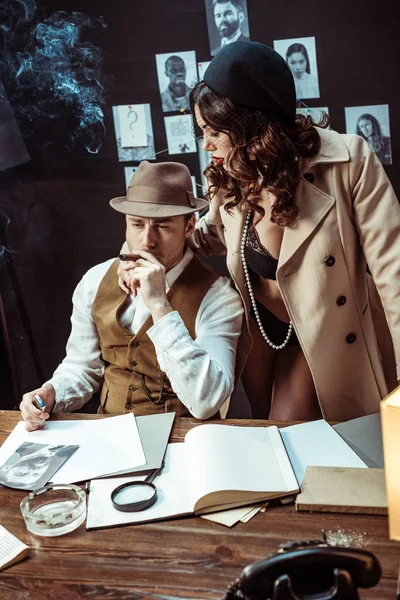 Mujer sexy en ropa interior y abrigo de trinchera seduciendo detective en la oficina - foto de stock