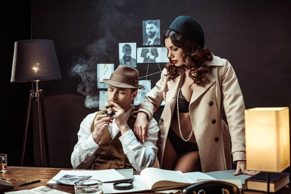 Mujer sexy en ropa interior y abrigo de trinchera seduciendo detective en la oficina - foto de stock