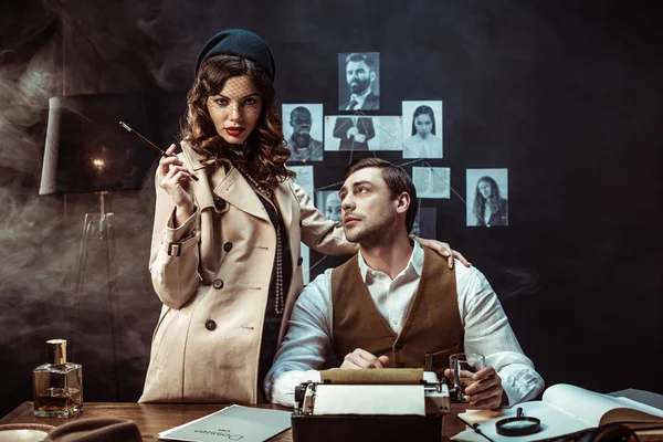 Woman with mouthpiece standing near detective in dark office — Stock Photo