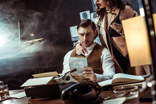Обрізаний вид сексуальної жінки в нижній білизні і траншеї пальто спокушає детектива в офісі — стокове фото