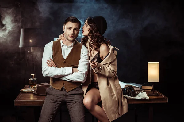 Sexy woman in lingerie and trench coat seducing detective in office — Stock Photo