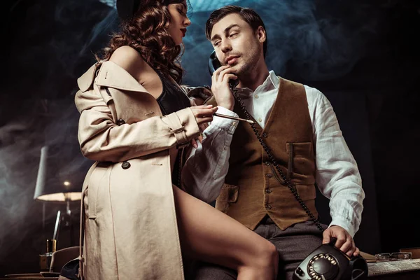 Low angle view of sexy woman in underwear and trench coat seducing detective in office — Stock Photo