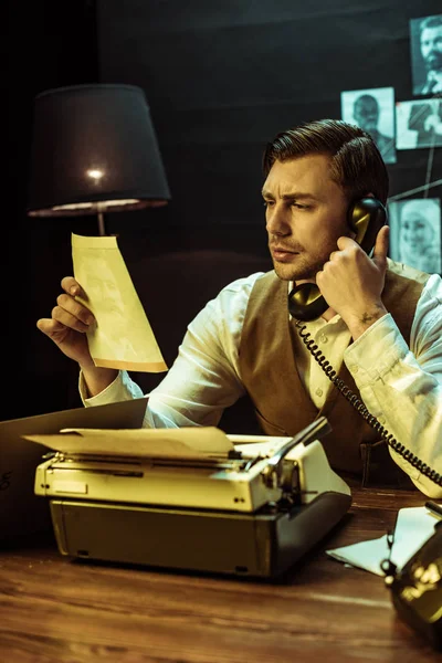 Detective reading document while talking on telephone in office — Stock Photo