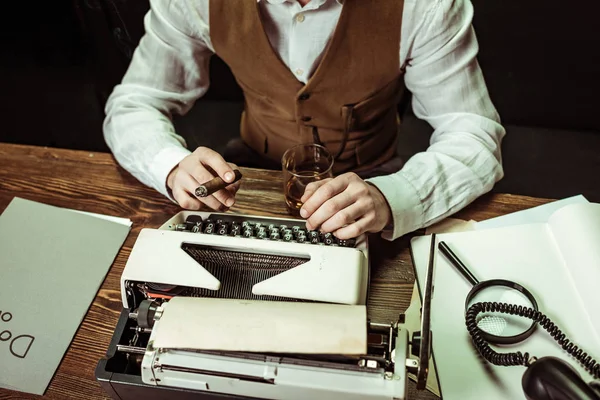 Vista parcial del detective con cigarro usando máquina de escribir en la oficina - foto de stock