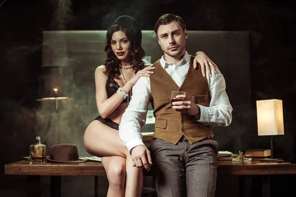 Sexy Frau in schwarzen Dessous sitzt auf Holztisch und flirtet mit Detektiv im Büro — Stockfoto