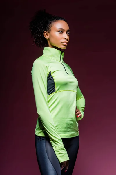 Beautiful african american sportswoman in track suit posing on dark — Stock Photo