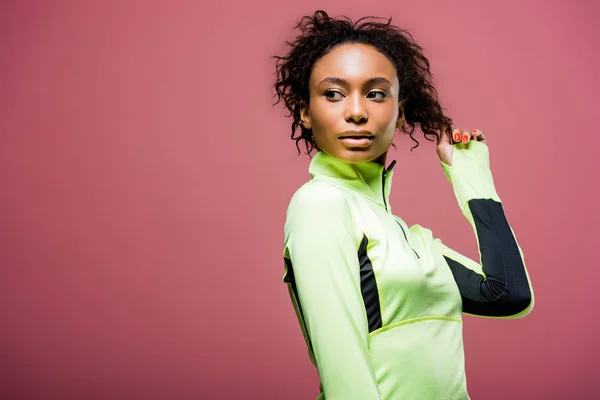 Belle sportive afro-américaine en veste de sport posant isolée sur rose avec espace de copie — Photo de stock