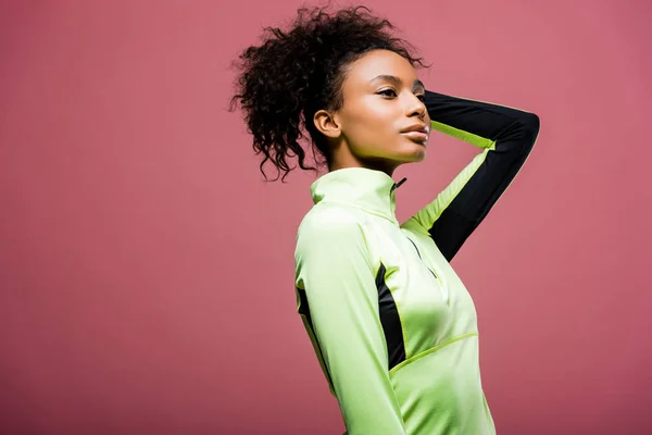 Hermosa afroamericana deportista en chaqueta de atletismo posando aislado en rosa con espacio de copia - foto de stock