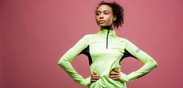 Panoramic shot of beautiful african american sportswoman in track jacket isolated on pink with copy space — Stock Photo