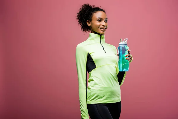 Beautiful african american sportswoman in track jacket with sport bottle isolated on brown with copy space — Stock Photo
