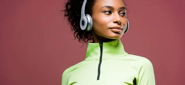Tiro panorâmico de bela esportista afro-americana em fones de ouvido isolados em marrom com espaço de cópia — Fotografia de Stock