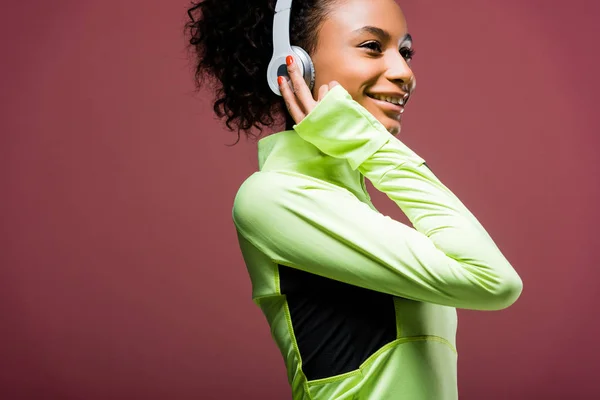 Beautiful smiling african american sportswoman in headphones isolated on brown — Stock Photo