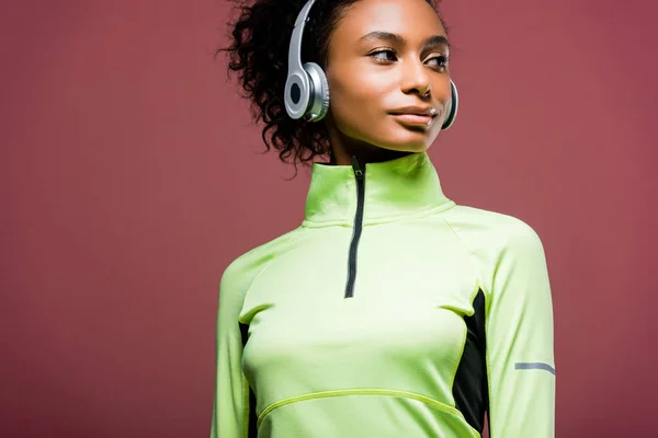 Красива афроамериканська спортсменка в навушниках дивиться ізольовано на коричневий колір з місцем для тексту — стокове фото