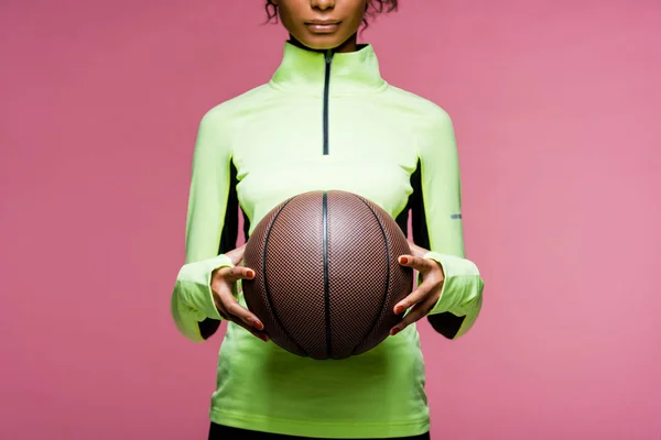 Vista recortada de la deportista afroamericana con baloncesto aislado en rosa - foto de stock