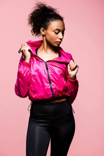 Attraente sportiva afroamericana in giacca a vento posa isolata su rosa — Foto stock