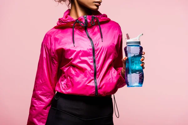 Vista recortada de la deportista afroamericana con botella de deporte aislado en rosa - foto de stock