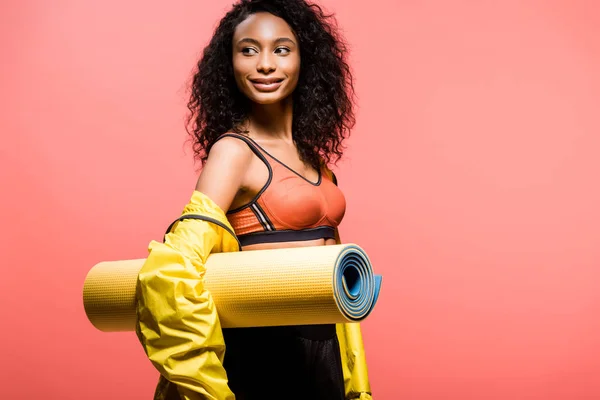 Beautiful african american sportswoman holding sport mat isolated on coral with copy space — Stock Photo
